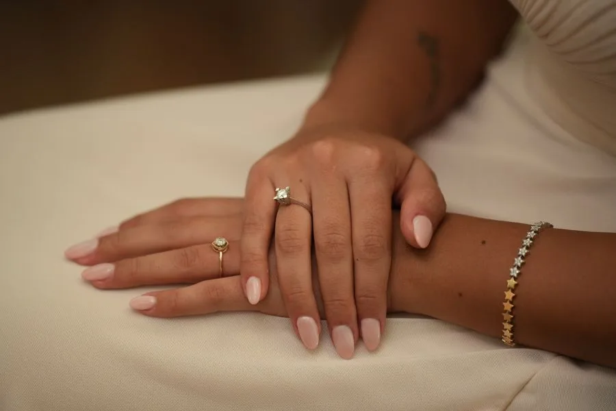 Close-up of a woman's hands with natural, well-groomed fingernails resting on a soft cream fabric