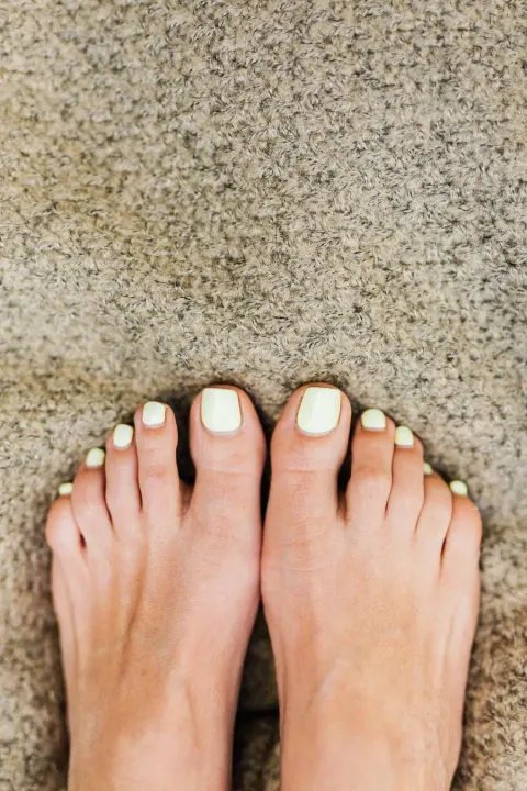 Close-up of a woman's bare feet with healthy, well-maintained toenails painted in a soft pastel color